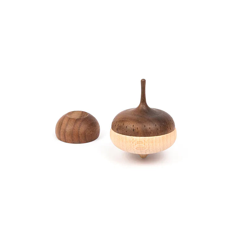 The Wooden Spinning Top - Acorn, featuring a rounded base and pointed tip, stands upright beside its matching dome-shaped wooden lid on a white background.