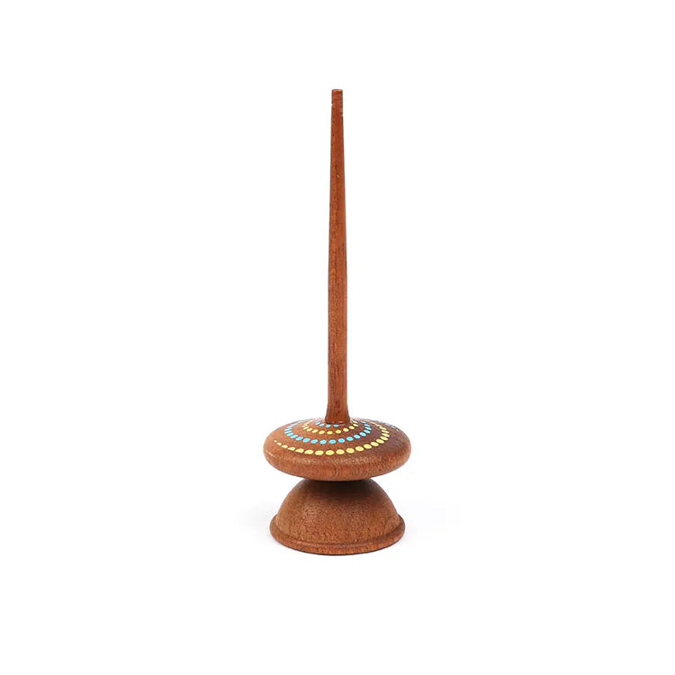 The Wooden Spinning Top - Long Stem, Dots is made from sustainable sapele wood and features a long handle, a rounded base, and a circular pattern of white and yellow dots on the top.