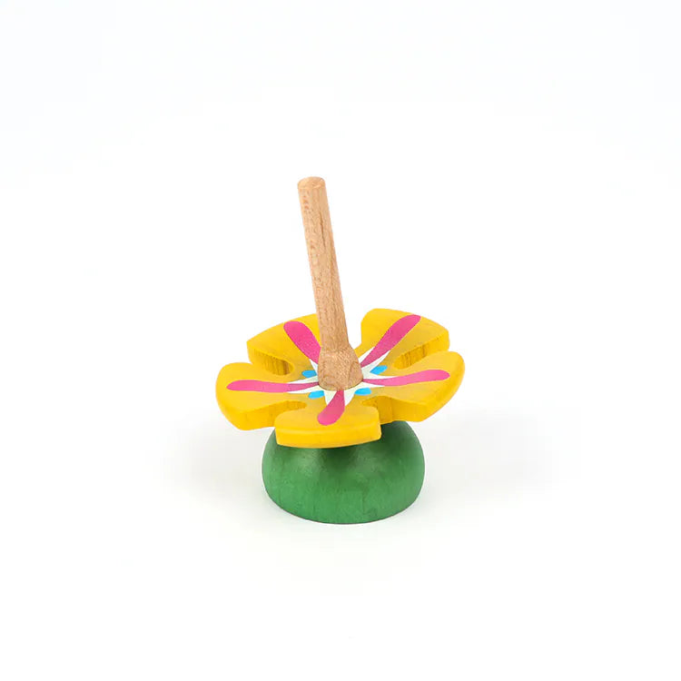 The Wooden Spinning Top - Yellow Flower features a sustainable beech wood design with a yellow flower shape, pink and blue accents, and a green base—perfect for timeless play. Set against a plain white background.