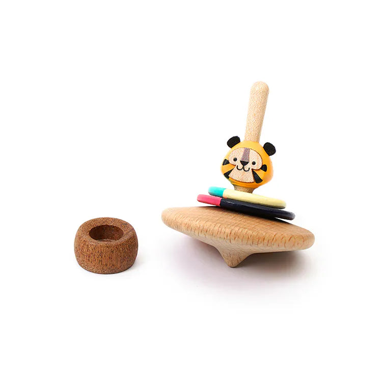 The Wooden Spinning Top - Tiger, crafted from sustainable wood and featuring a smiling tiger face with colorful rings, rests beside a small brown ring on a white background—a delightful nod to classic play.
