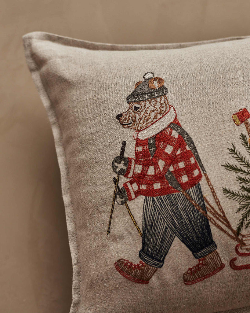 The Coral & Tusk Christmas Tree Sled Pillow features an embroidered bear in winter attire—red plaid jacket, scarf, hat—holding ski poles against a neutral background for a festive holiday touch.