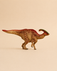 A large, realistic Schleich Parasaurolophus dinosaur toy featuring a green and red crest, brown body, and striped pattern stands on a beige background—ideal for Schleich dinosaur enthusiasts or anyone looking for a unique dinosaur gift.