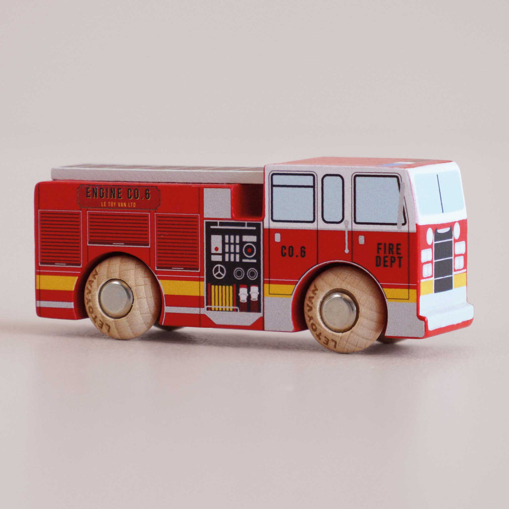 A small, toy wooden fire engine—No. 44 GT270 Quinn, made in England—painted red with yellow and black details, labeled “Fire Dept” and “Engine Co. 6” on the side, with two visible wooden wheels—perfect for imaginative adventures and daring rescue missions.