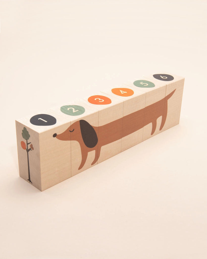 A set of Uncle Goose Environments Neighborhood Blocks arranged in a line, forming an illustration of a brown dachshund with numerical and pictorial representations, including a carrot graphic on block number one.
