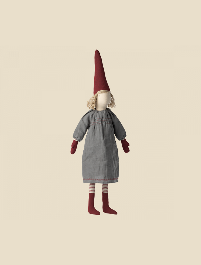 An illustration of a Maileg Christmas Small Pixy doll with a long red pointed pixy hat, a neutral facial expression, and wearing a gray dress with striped stockings against a light background.