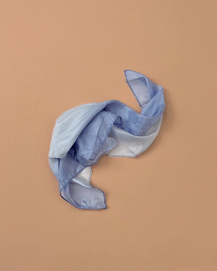 Sarah's Silks Earth Playsilk - Stone is a light blue, translucent silk made from 100% pure silk, loosely twisted and displayed on a solid beige background.