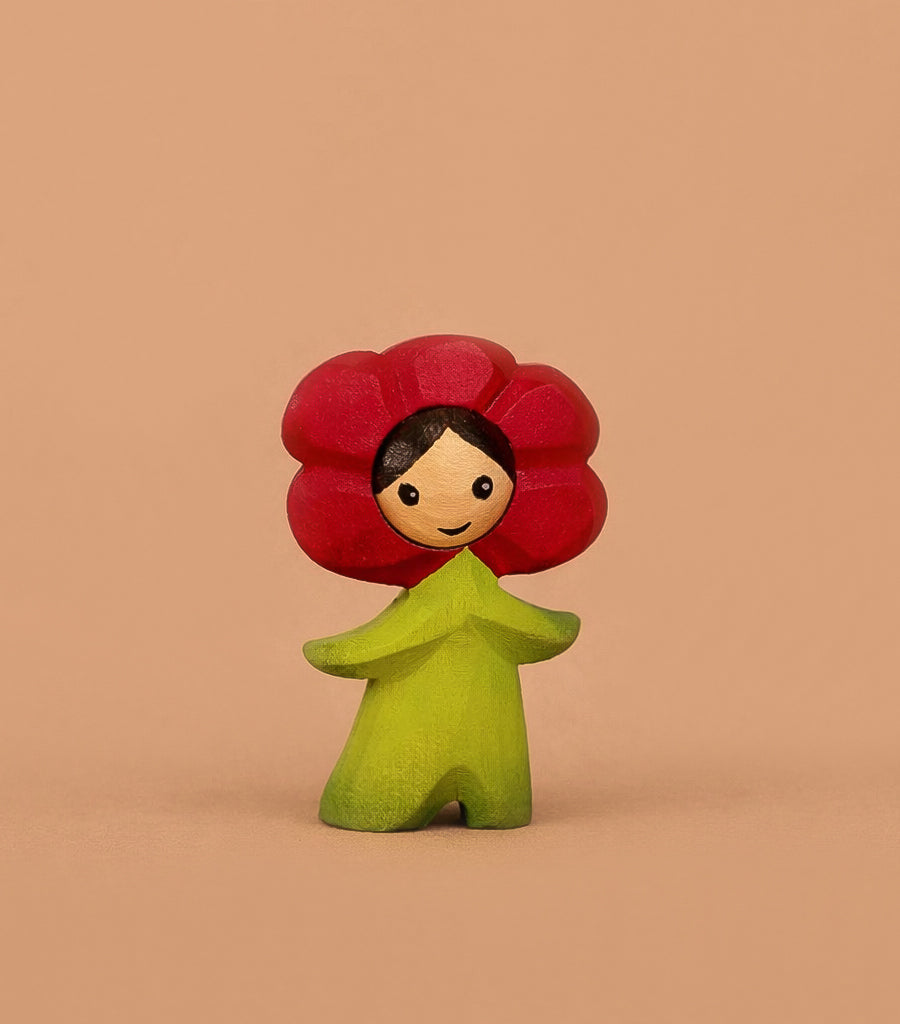 The Bumbu Handmade Wooden Flower Child Poppy features a red flower-shaped head, smiling face, and green body—perfect for Montessori toys or small world play—standing against a plain beige background.