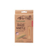 The Huckleberry Grass Whistle package shows a child using the wooden whistle with green grass blades, encouraging kids to connect with nature—ideal for outdoor hiking fun.