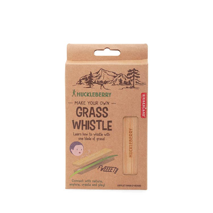 The Huckleberry Grass Whistle package shows a child using the wooden whistle with green grass blades, encouraging kids to connect with nature—ideal for outdoor hiking fun.