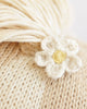 Close-up of Cuddle + Kind Sophia the Pony’s cream-colored yarn and knitted fabric, adorned with a small crocheted white flower with a yellow center—expertly handmade in Peru using fair trade practices.