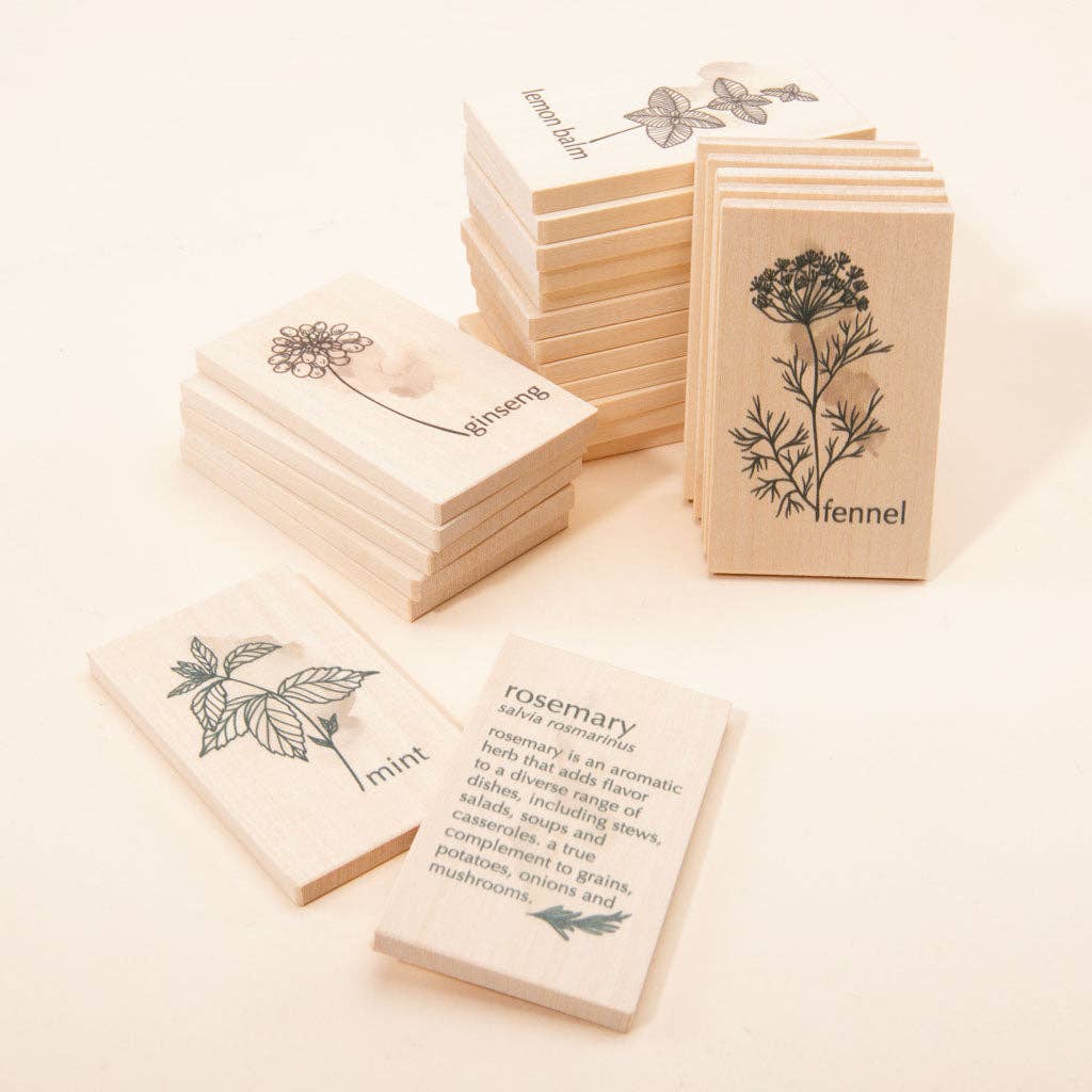 The Uncle Goose Chips - Herbs are wooden tiles made from sustainable basswood, featuring engraved botanical illustrations and the names of herbs such as fennel, rosemary, savory, and mint. Arranged neatly against a cream background, one tile provides a brief description of the uses of rosemary.