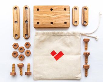 A solid Handmade Wooden Building Tool Set displayed on a white background, including various screws, nuts, and wooden parts alongside a canvas bag with a red diamond logo. Suitable for children 3 and older.