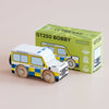 A wooden police car, titled “No. 40 GT250 Bobby | Made in England,” is displayed beside its box, which bears the same name and features a matching image of the toy. Styled after a classic British patrol vehicle, the car sports blue and yellow markings with “POLICE” on its side—ideal for imaginative play.