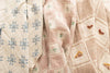 The Organic Cotton Baby Blanket - Farm features three vintage-style quilts with soft, muted tones: blue star embroidery on the left, small flowers in the center, and chickens, flowers, and a house embroidered on the right.