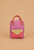 A Sticky Lemon Backpack Small - Envelope in Rosebay Pink is displayed against a plain beige background, showcasing its small rectangular waterproof design with pink material, red handles, a yellow flap, a red checkered front pocket, and adjustable shoulder straps.
