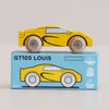 A yellow wooden sports car from the “No. 19 GT105 Louis” collection sits atop a blue box labeled “GT105 LOUIS,” featuring a matching car illustration. Reminiscent of classic Le Toy Van designs, the box highlights features such as sustainable wood, child-safe paints, and manufacturing in England.