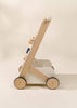 The Wooden Activity Walker is displayed in side view against a neutral background, showcasing its four-wheeled, minimalist wooden design and emphasizing its role as an ideal activity walker for supporting little ones taking their first steps.