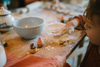 A young child rolls dough at a flour-dusted table with the Grapat Play Set - Bakes, surrounded by sustainable wooden toys and a bowl, inspiring creative baking fun.