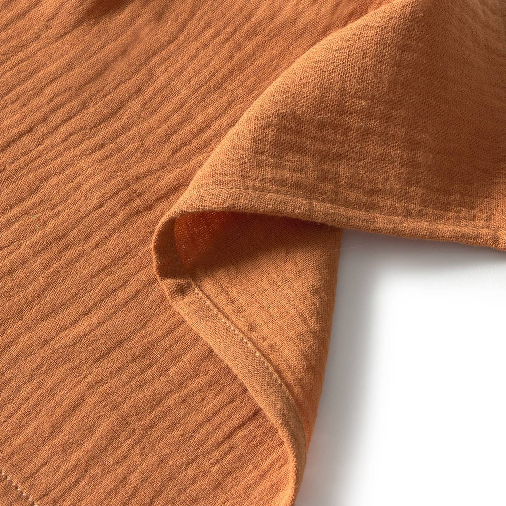 A close-up of Pepa the Apple Big Doudou, a textured light orange organic cotton baby comfort toy, with a folded corner highlighting its weave and thickness against a white background.