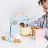 A young child enjoys pretend play with the Bakers Mixer Set & Accessories, featuring a pastel wooden mixer, bowl, rolling pin, egg, jar, and pink "Sucre" box—perfect for any toy kitchen.
