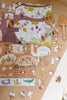 The Beneath the Branches 200 Piece Puzzle with animal characters lies partially assembled on wood beside a plush mouse and two wooden utensils. Matte pieces, some loose, are scattered near the edge of a white rug.
