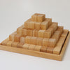 A Grimm's Large Natural Stepped Pyramid is placed on a square wooden tray. The blocks are arranged in a step-like, tiered manner, starting with a large base and tapering to a single block at the top. This wooden toy has a natural, unfinished appearance.