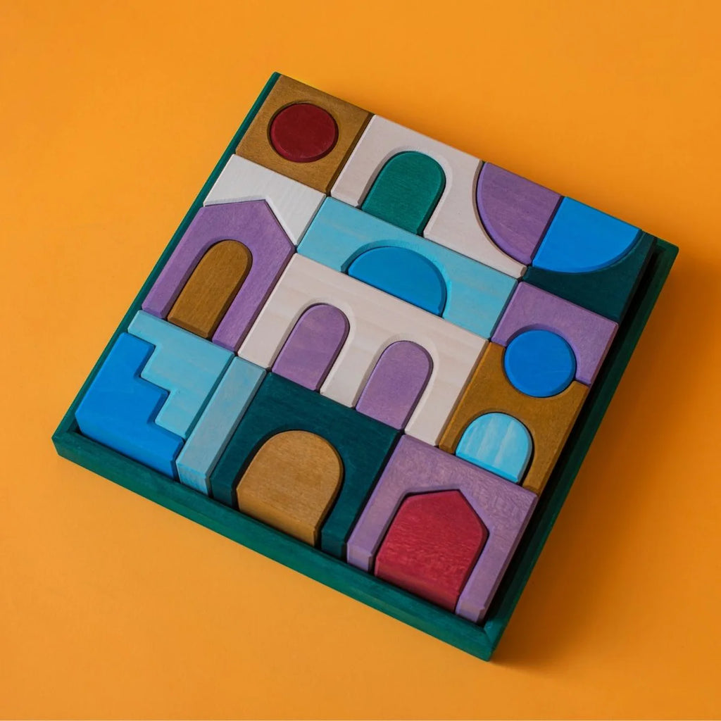 Grimm's Small Building Set - Floors comes in a square tray featuring colorful wooden blocks in arches, rectangles, and circles. The pieces are arranged mosaic-style on a bright orange background, ideal for imaginative creations.