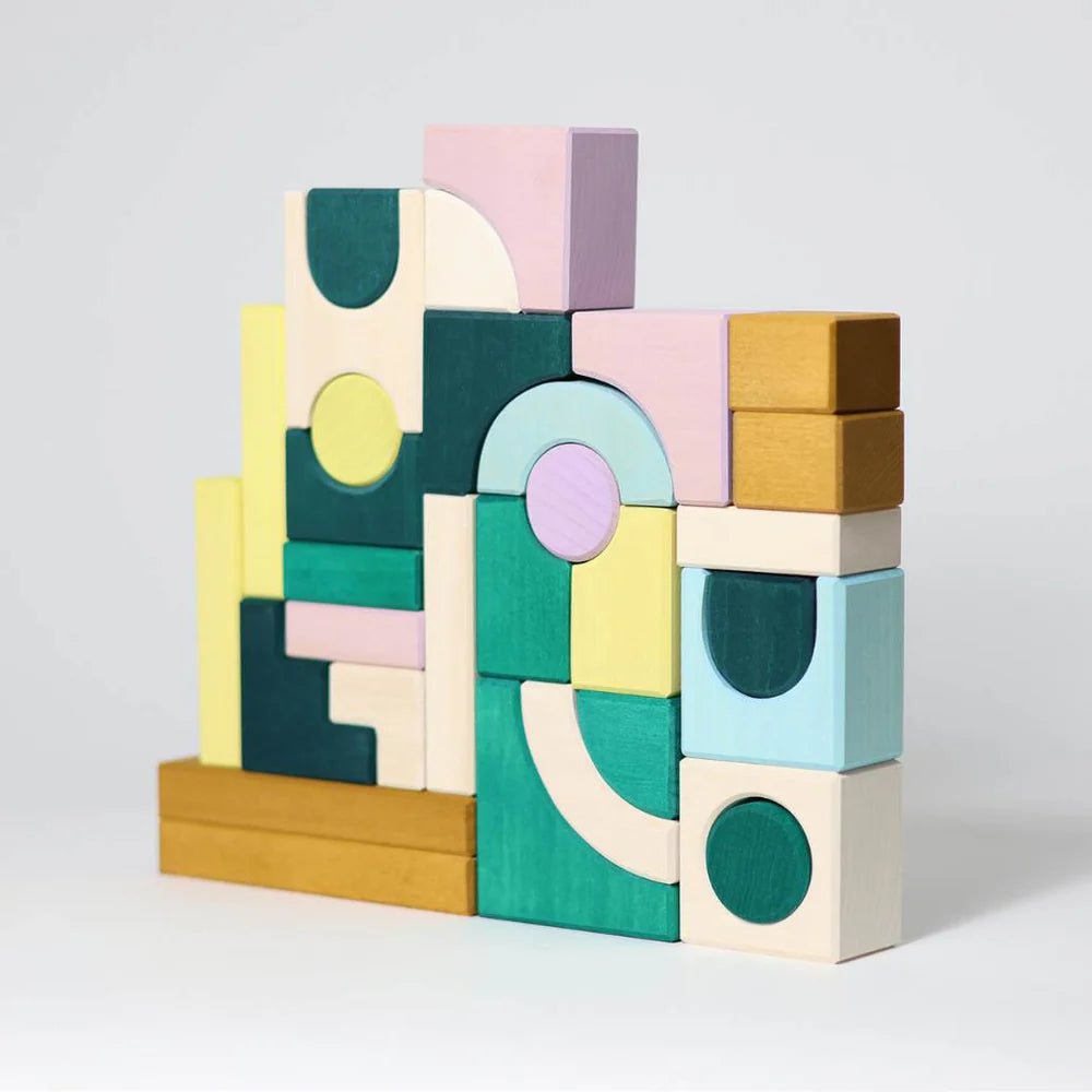 A stack of pastel wooden blocks forms an abstract geometric structure against a white background, featuring Grimm's Small Building Block Set - Movement from the TINY ART COLLECTION.