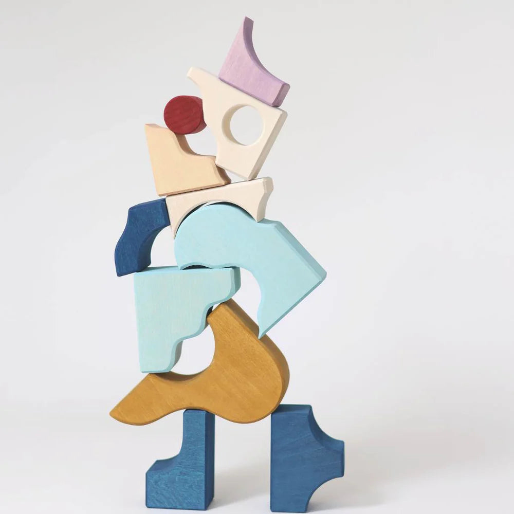 Grimm's Small Building Block Set - Wave features colorful, uniquely shaped wooden blocks stacked together against a plain white background, creating an abstract and whimsical figure.