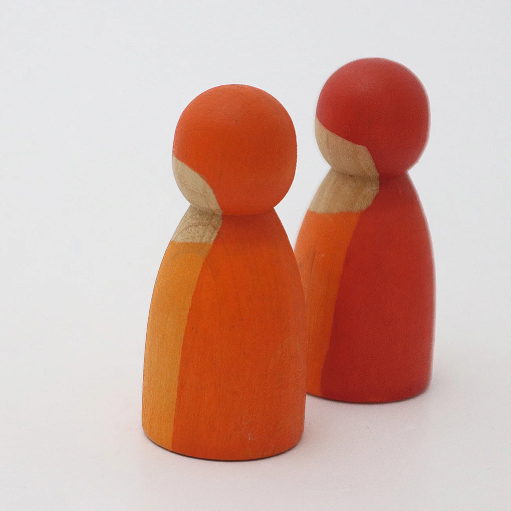 Two orange and red wooden peg dolls from the Grimm’s Building World - Desert Sand set, perfect for imaginative free building.