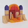 Grimm’s Building World - Desert Sand natural wood toy building blocks constructed into a castle gatehouse with two small peg dolls standing on the front steps.