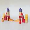 Two sets of Grimm’s Building World - Desert Sand wooden blocks arranged to form arched structures and staircases, each accompanied by a small wooden peg person for imaginative free building.