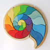 A Grimm’s Building Set Ammonite Shell featuring spiral-shaped wooden building blocks with interlocking, rainbow-colored pieces arranged to resemble an ammonite shell.
