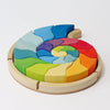 A colorful Grimm’s Building Set Ammonite Shell arranged in a spiral ammonite shell shape inside a circular tray to form a creative puzzle.