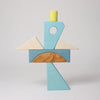 The Grimm's Building Set - Blue includes wooden blocks and blue pieces arranged to resemble a bird with a yellow cylinder head, white triangle wings, and a blue and natural wood body—perfect for inspiring creativity in toddlers.