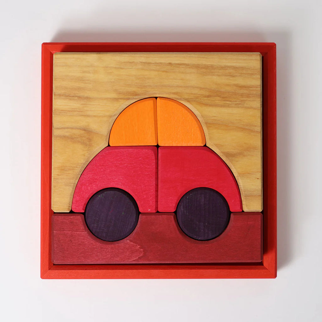 Grimm's Building Set - Red is a vibrant wooden puzzle in a red frame, featuring block pieces that form a simple car with an orange and yellow top, red body, two dark wheels, and a brown base.