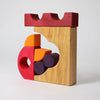 The Grimm's Building Set - Red showcases colorful wooden blocks in red, yellow, orange, and purple, featuring geometric shapes like circles and arches stacked vertically against a plain white background.