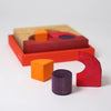 Grimm's Building Set - Red features colorful wooden pieces—a yellow quarter circle, purple cylinder, and red crescent—arranged on a matching puzzle board with recessed spaces. Perfect for engaging color building block play.