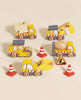Four wooden toy construction vehicles with red and white stripes, four traffic cones, and a small construction sign are arranged on a beige surface—ideal to pair with the Easter Basket Gift Set for imaginative play.