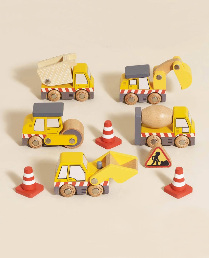 Four wooden toy construction vehicles with red and white stripes, four traffic cones, and a small construction sign are arranged on a beige surface—ideal to pair with the Easter Basket Gift Set for imaginative play.