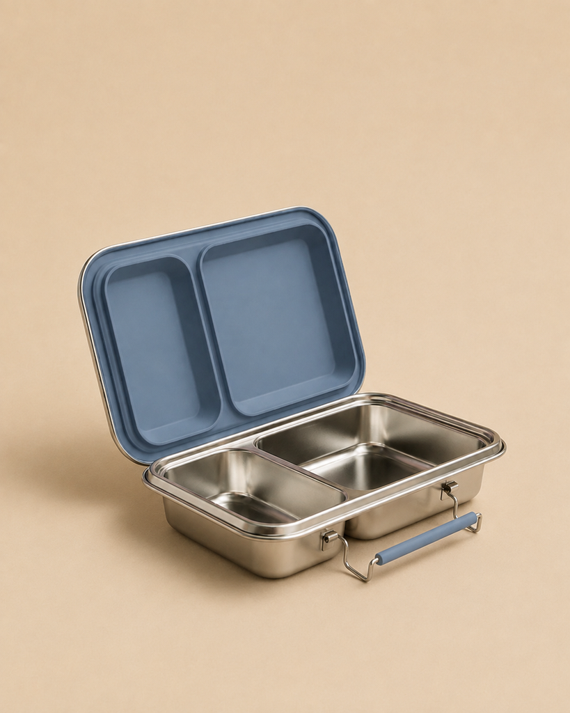 Haps Nordic - Stainless Steel Lunch Box with two compartments and an ocean blue silicone-sealed lid sits open on a beige background—this eco-friendly container keeps your meals organized and fresh.