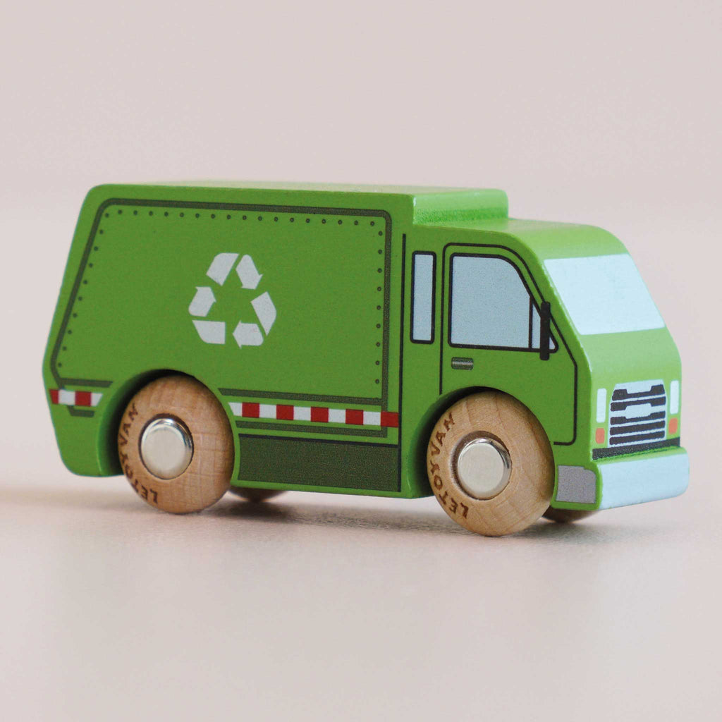 Introducing the No. 36 GT200 Rudy | Made in England: a green wooden recycling truck with durable wooden wheels and a white recycling symbol on its side, set against a light pink background—perfect for sustainable play and an eco-friendly toy choice.