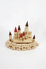 The Great Kingdom Building Set, a charming wooden construction kit, includes multiple towers with red and brown conical roofs, smooth-edged walls, and arched entryways. Meticulously crafted using non-toxic paint, this captivating toy is displayed against a crisp white background.