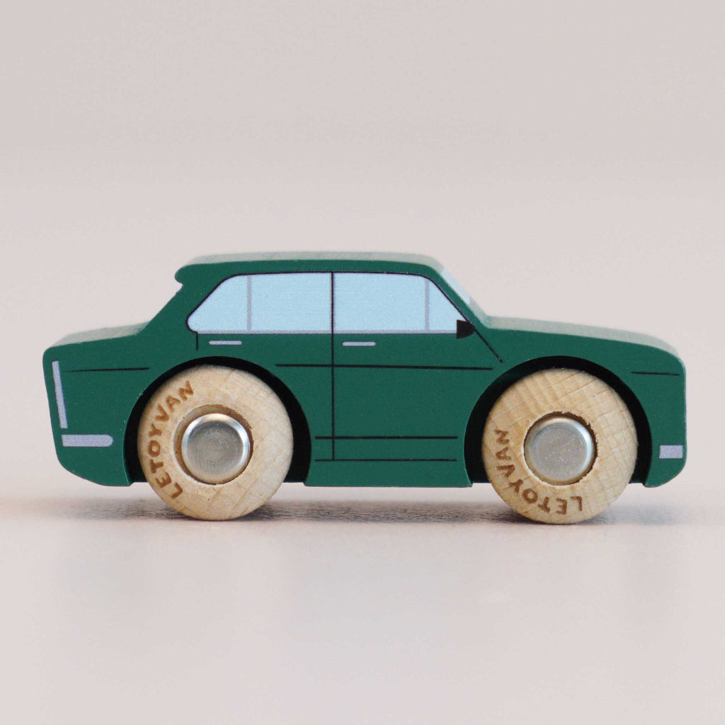The No. 3 GT20 Tommy, made in England, is displayed in a side view on a plain light background, featuring a classic wooden design with a green body, light blue windows, and natural wood wheels that evoke the charm of a nostalgic toy.