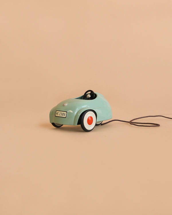The Maileg Car, Mouse - Light Mint (ships in 1-2 weeks), a small mint-green pull-along car featuring white and orange wheels and a black pull string, sits on a plain beige background.