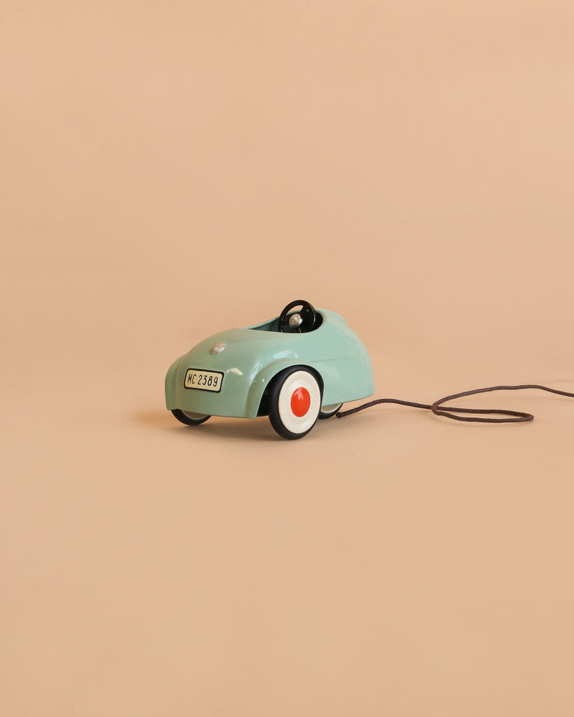 The Maileg Car, Mouse - Light Mint (ships in 1-2 weeks), a small mint-green pull-along car featuring white and orange wheels and a black pull string, sits on a plain beige background.