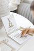 A child uses a water pen to reveal an illustration of a birthday cake on a Winnie-the-Pooh: Pooh’s Birthday Surprise (Water Reveal) spiral-bound book featuring a drawing of Rabbit.
