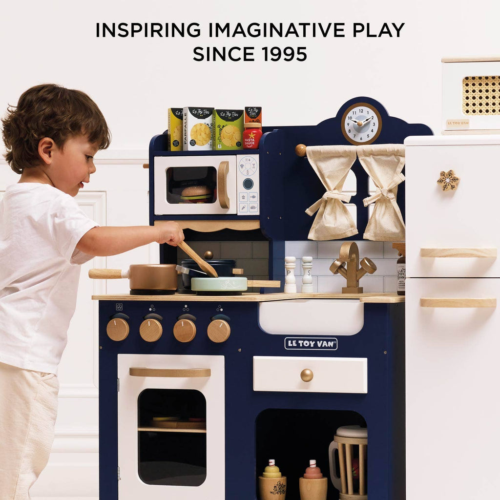A young child plays with a blue and white Pots & Pans Kitchen Accessories toy cooking set.