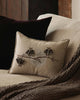 The Coral & Tusk Bat Branch Pillow, featuring embroidered black bats on beige linen, rests on a light couch beside a brown blanket and velvet cushion—an ideal subtle touch for Halloween décor. Ships in one week.