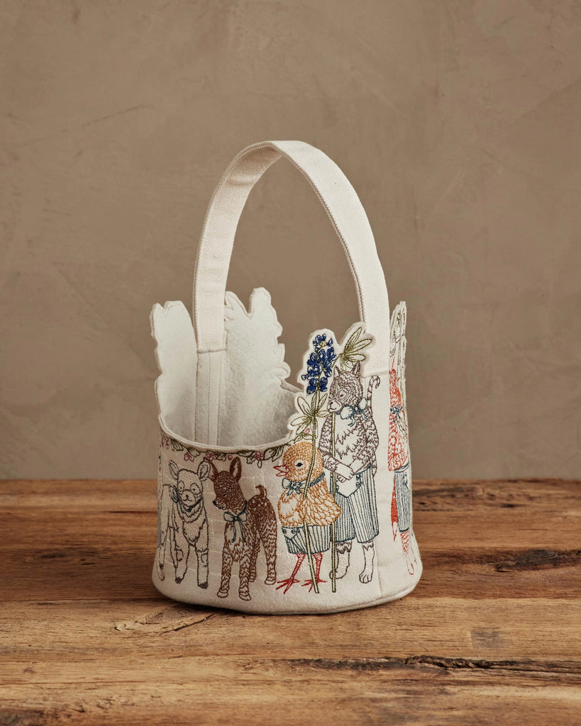 The Coral & Tusk Easter Parade Basket is a small embroidered basket with a handle, featuring animals in clothes holding flowers—perfect as a felt Easter basket or charming holiday accent.